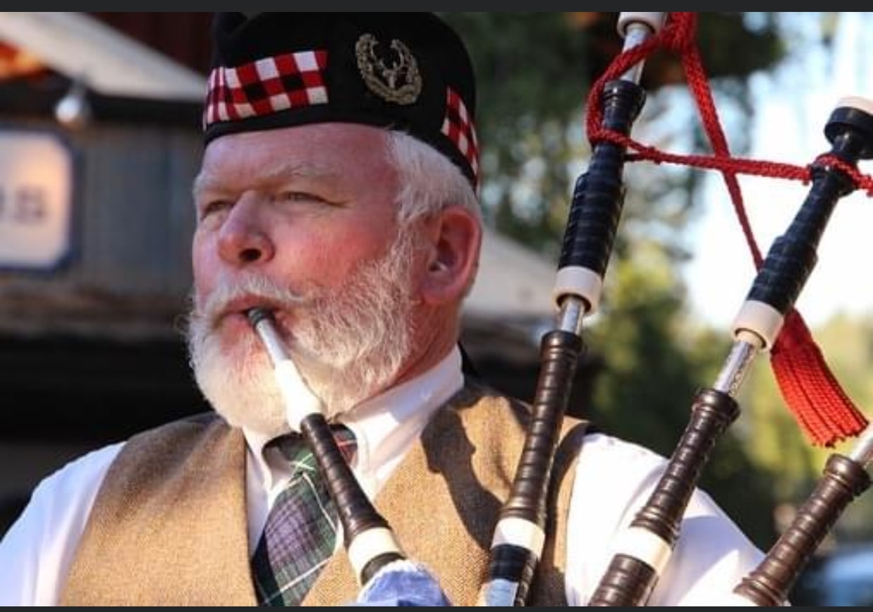 Close-up of Bruce Locken playing bagpipes in Highland cap