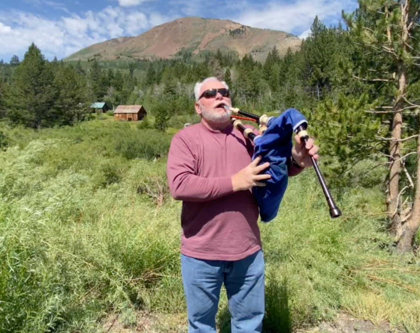 Bruce Locken playing bagpipes outdoors at 7000 feet in the mountains