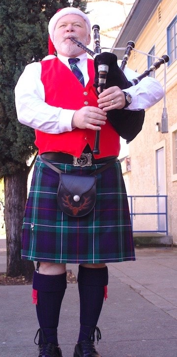 Bruce Locken playing bagpipes in kilt with Santa hat