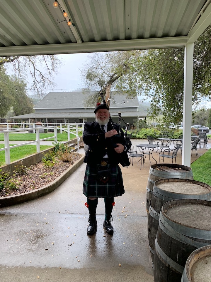 Bruce Locken playing bagpipes at a winery in the rain